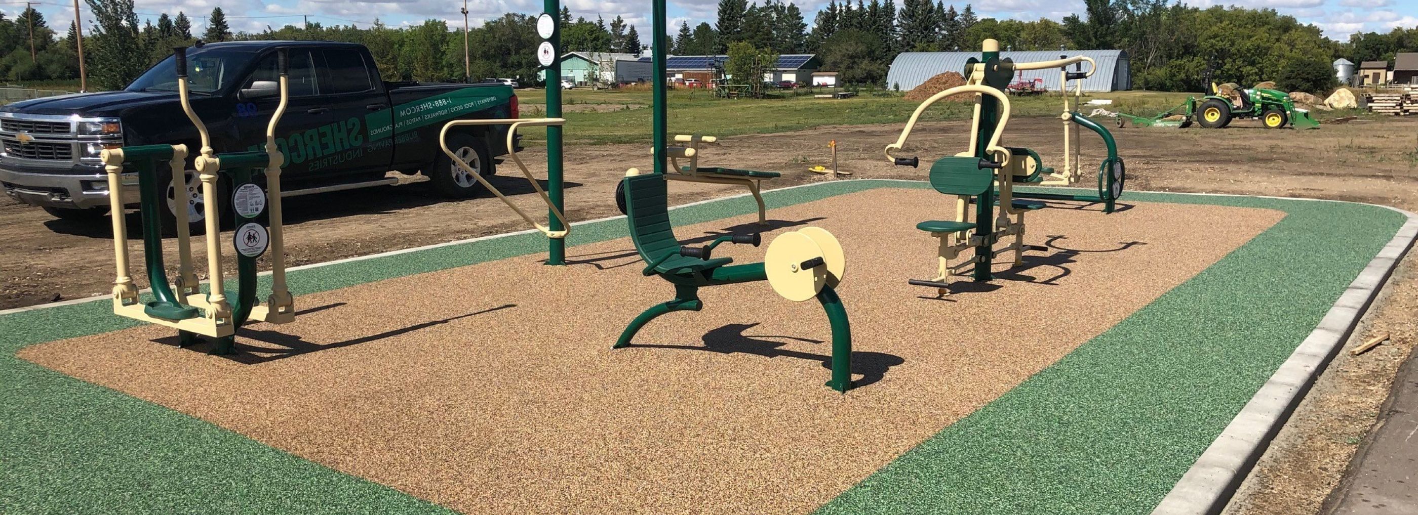 Green and sandy coloured rubber flooring at an outdoor gym.