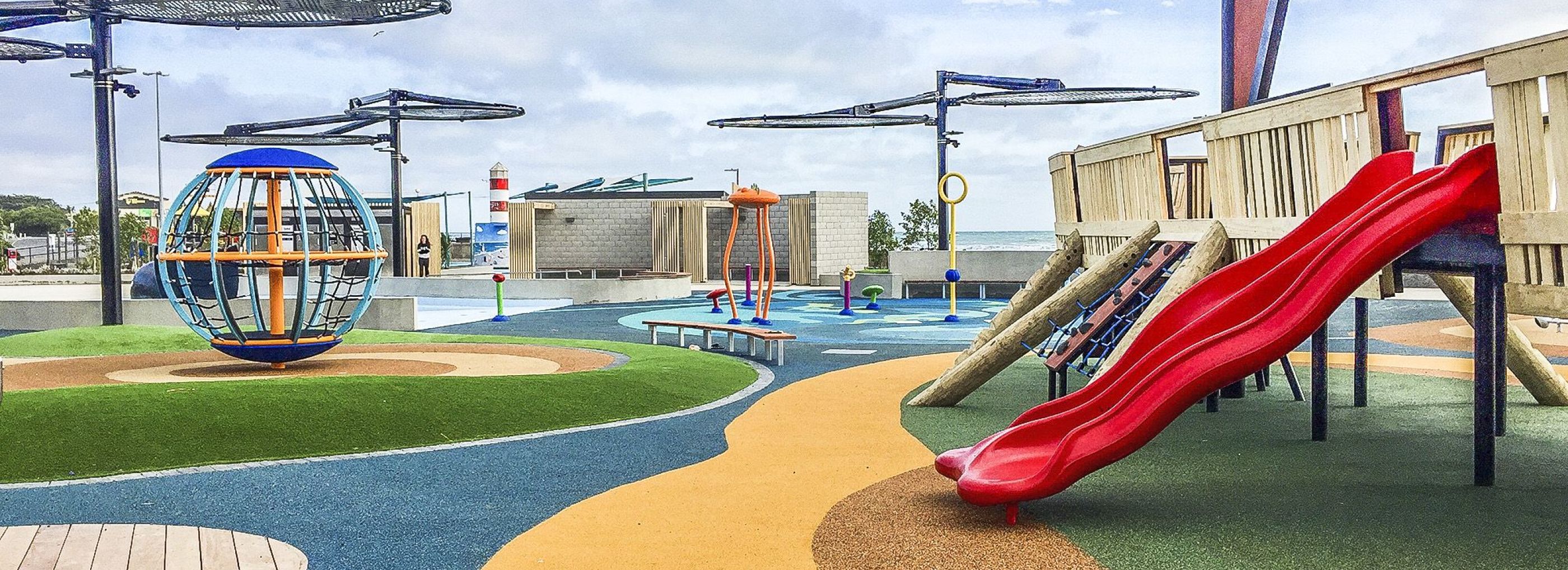 Outdoor playground with multi-coloured rubber flooring.